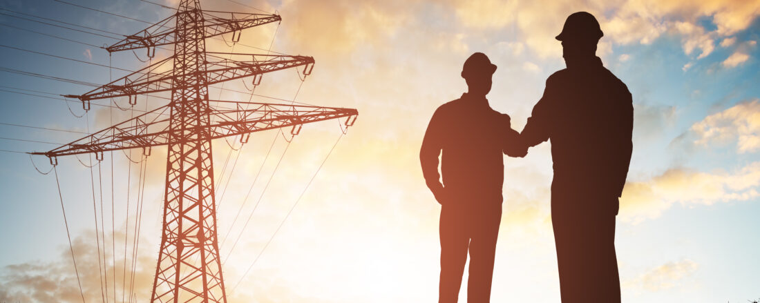 Silhouette,Of,Two,Engineers,Shaking,Hands,With,Electricity,Pylon,Against